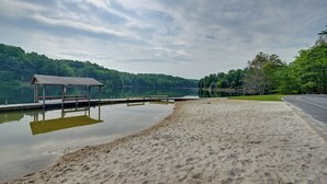 A sandy beach with a wooden dock and a covered structure. - Festive Lakefront Escape: Blue Ridge Holiday Home (Brevard)