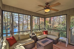 A sunroom with large windows, a ceiling fan, and a seating area with cushions. - Festive Lakefront Escape: Blue Ridge Holiday Home (Brevard)