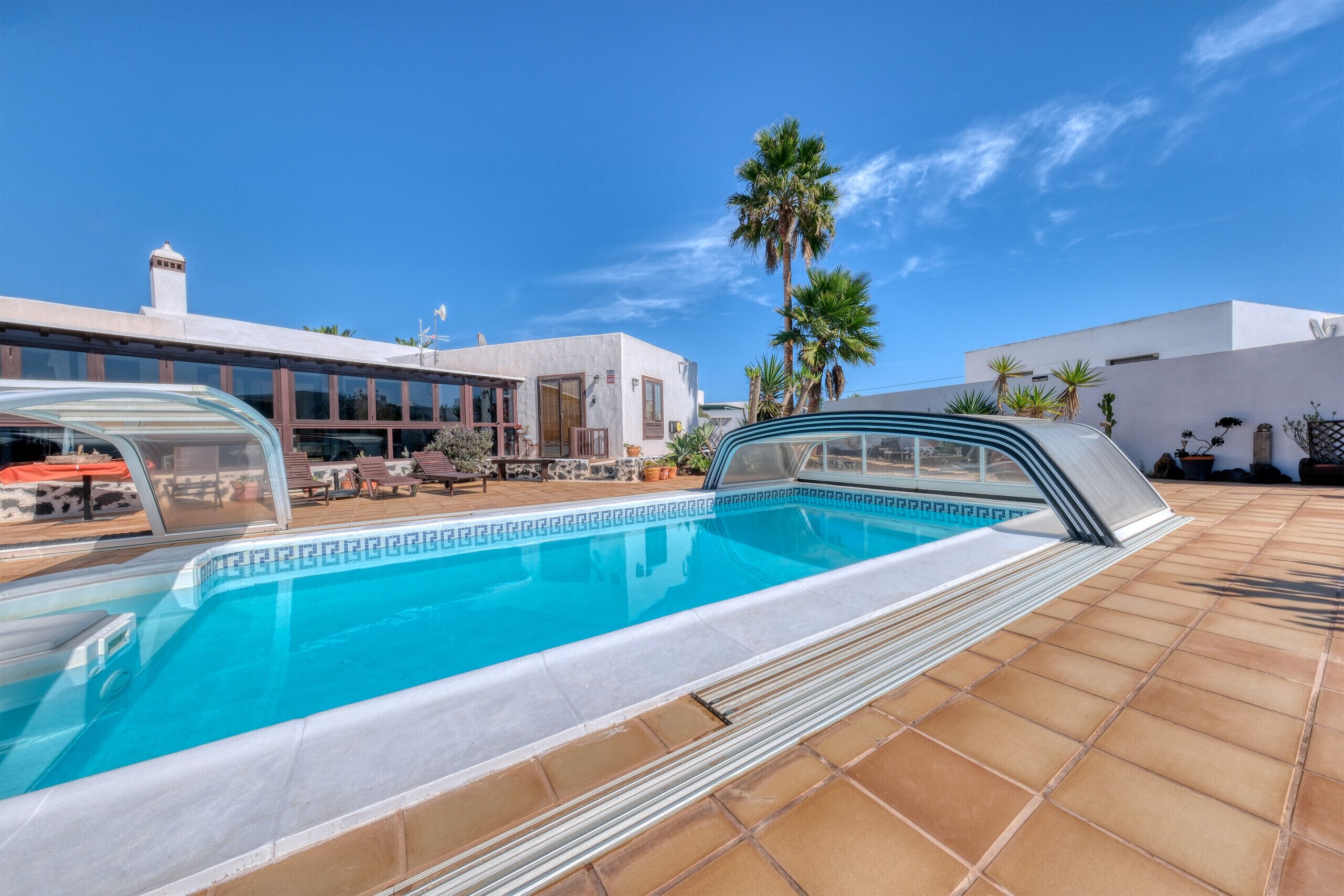 Une piscine dotée d’un bassin aux eaux d’un bleu limpide, entourée d’une terrasse carrelée.