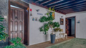L’entrée d’un hôtel, avec une porte en bois, un pot de fleurs et une enseigne indiquant « CASAMELA ».