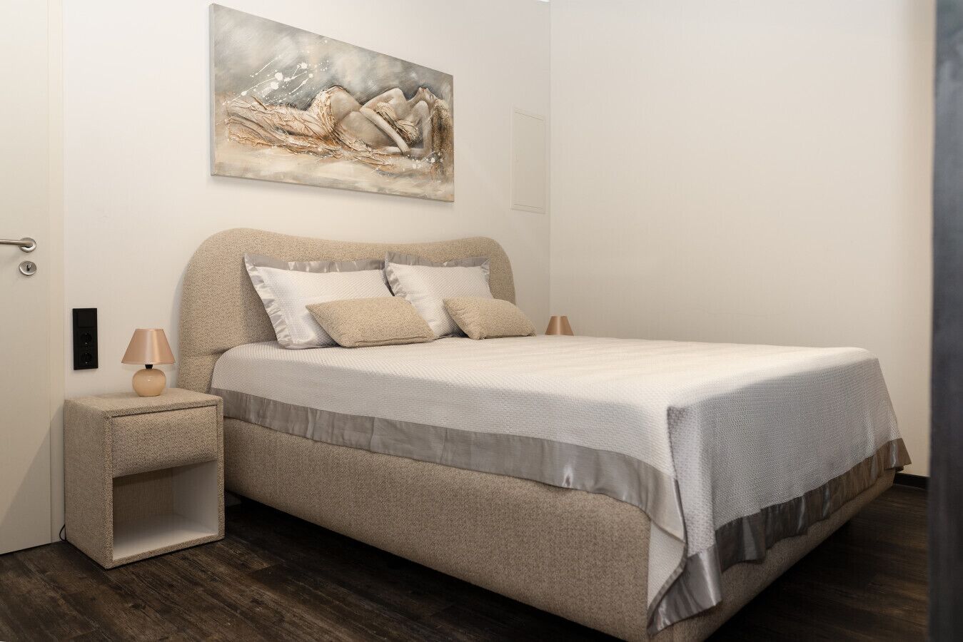 Une chambre à coucher avec un lit, des tables de chevet, une lampe et un tableau au mur.