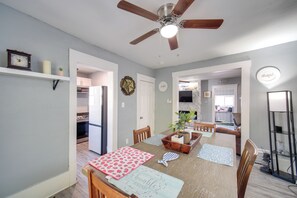 A dining area with a wooden table, chairs, and a ceiling fan. There are shelves with decorative items and a clock on the wall. - Modern & Convenient! Group Stay in Highland Square (Akron)