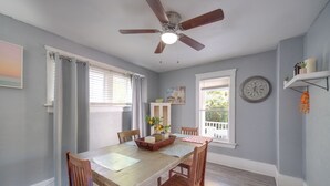 Comedor con mesa de madera, sillas, ventilador de techo y ventana con vista.