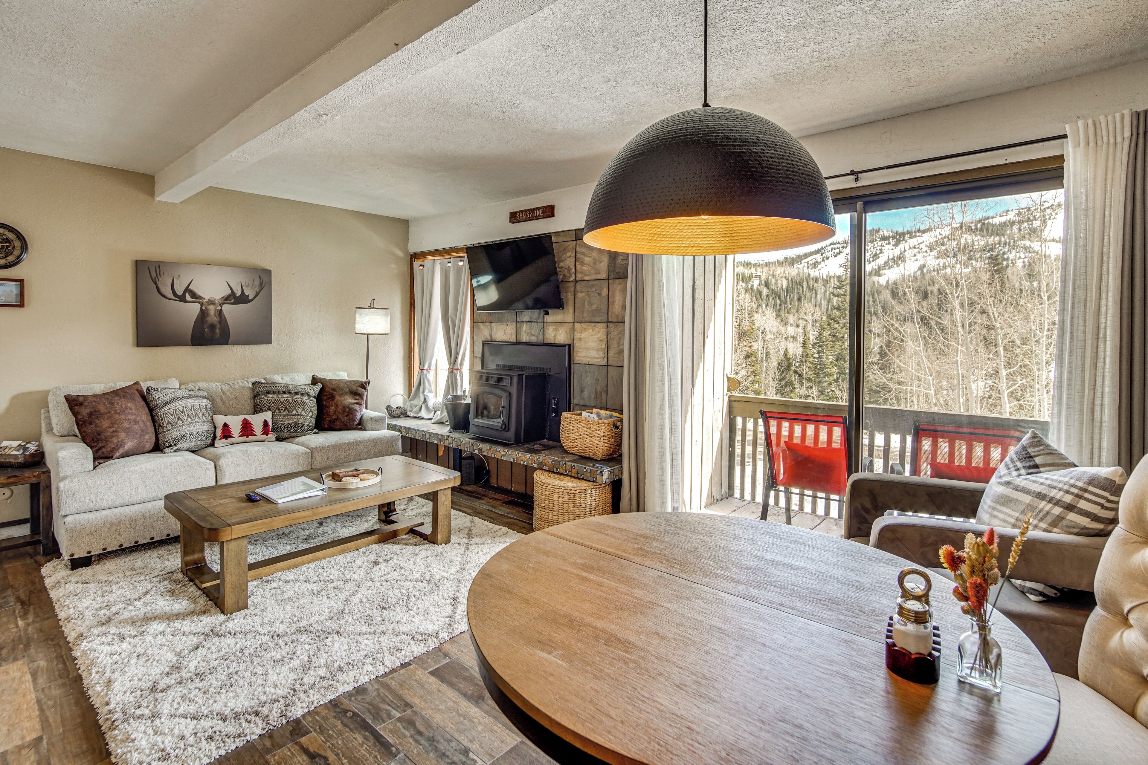 A cozy living room with a fireplace, a sofa, a coffee table, and a view of the outdoors.