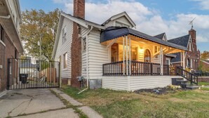 A single-story house with a front porch, a brick chimney, and a metal gate. - Easy Dtwn Detroit Access: Pet-friendly Family Home (Detroit)