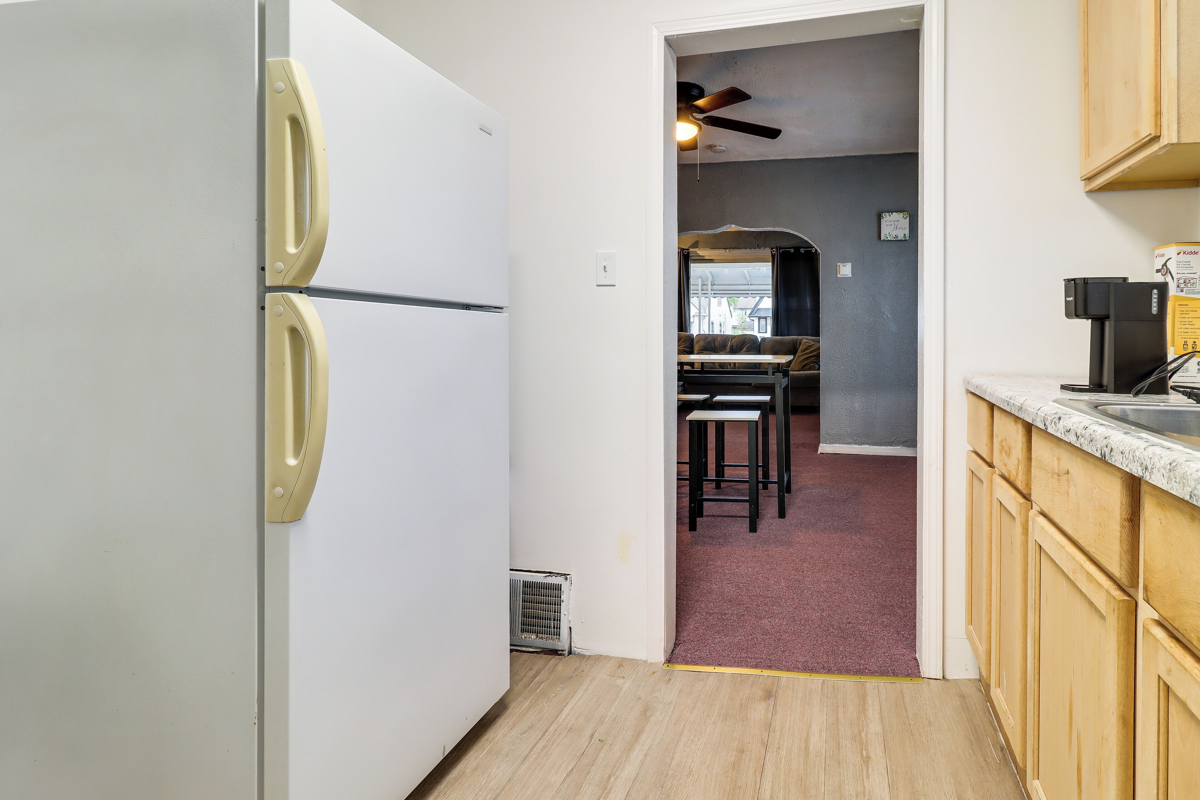 A kitchen with a white refrigerator, wooden cabinets, and a ceiling fan.