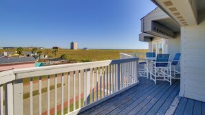 Une terrasse en bois avec une balustrade blanche donnant sur une plage.