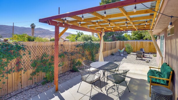 A covered patio with a table and chairs, a wooden fence, and a view of mountains. - Family Home, 7 Mi to Joshua Tree National Park! (Twentynine Palms)