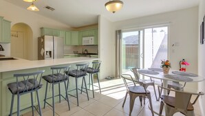 A modern kitchen with a central island, bar stools, and a dining table with chairs. - Family Home, 7 Mi to Joshua Tree National Park! (Twentynine Palms)