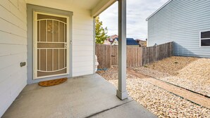 A house with a front porch, a wooden fence, and a gravel driveway. - Fenced-in Yard w/ Deck: Pet-friendly Lochbuie Home (Brighton)