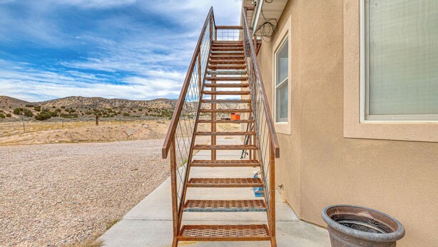 A metal staircase leading to a building's entrance, a concrete pathway, and a large planter next to the building. - Near Dinosaur Nat'l Monument! High Desert Hideaway (Vernal)
