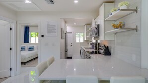 A modern kitchen with white cabinetry, a central island, and a dining area with white chairs. - Couple's Retreat 1 Mi to Fort Lauderdale Riverwalk (Fort Lauderdale)