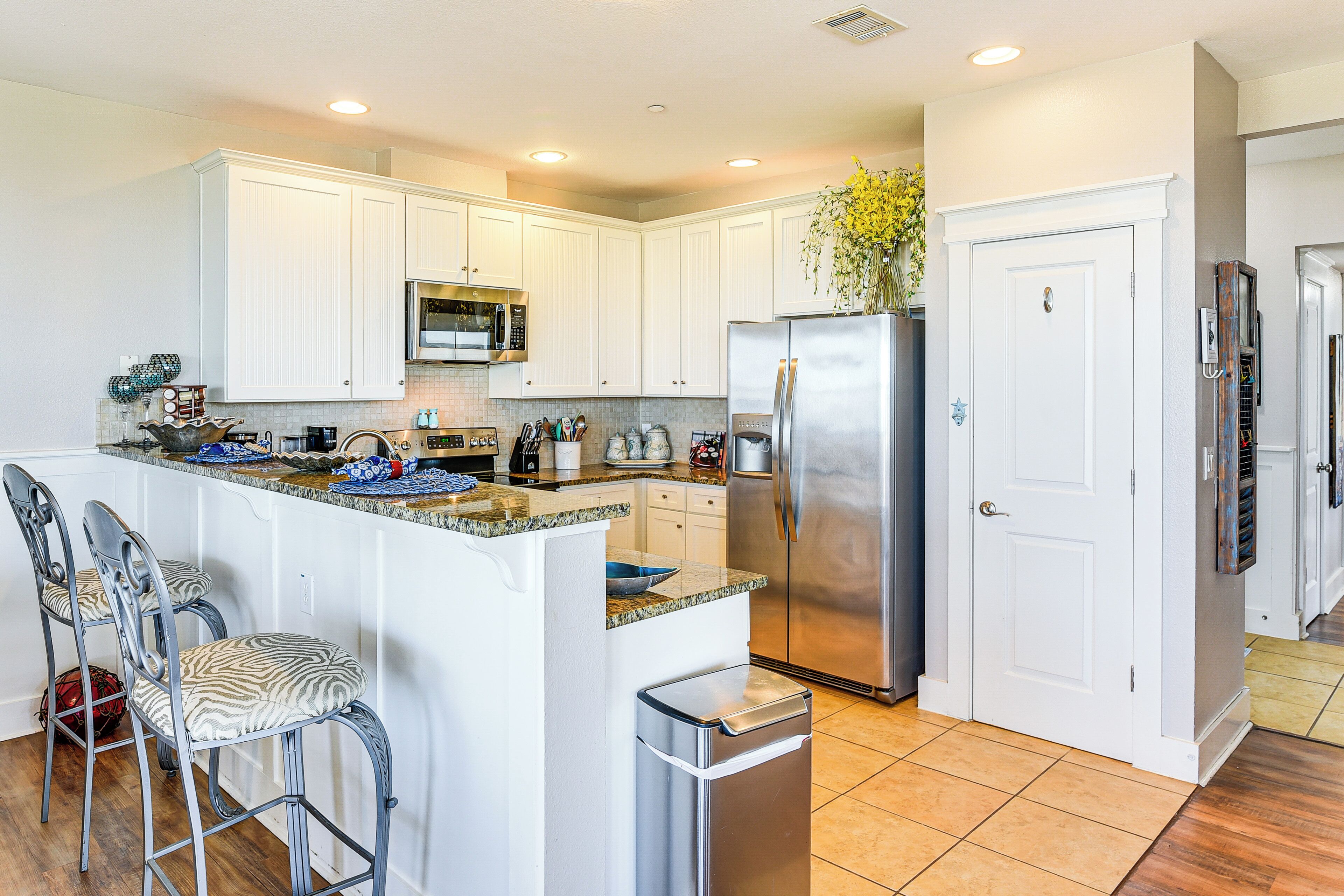 A kitchen with white cabinets, stainless steel appliances, and a center island with bar stools.