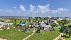 A resort with a pool, palm trees, and a view of the ocean. - Steps to Private Beach: Galveston Resort Condo! (Galveston)
