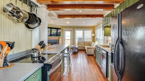 Una cucina con pavimento in legno, un frigorifero nero e pentole appese.