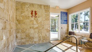 A spa area with a glass floor, tiled walls, and a view of the outdoors through a window. - Fairway Views! Resort-style Condo in Sunset Beach (Sunset Beach)