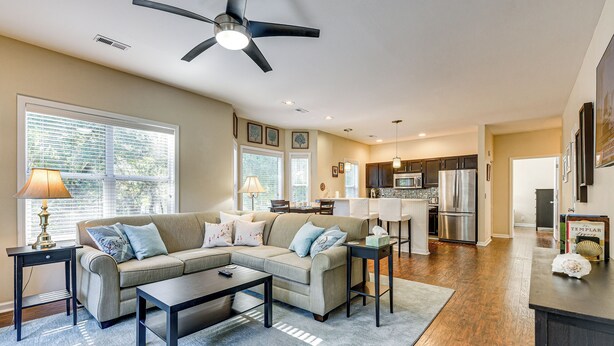A spacious living room with a sectional sofa, a coffee table, and a dining area with a kitchen in the background. - Fairway Views! Resort-style Condo in Sunset Beach (Sunset Beach)