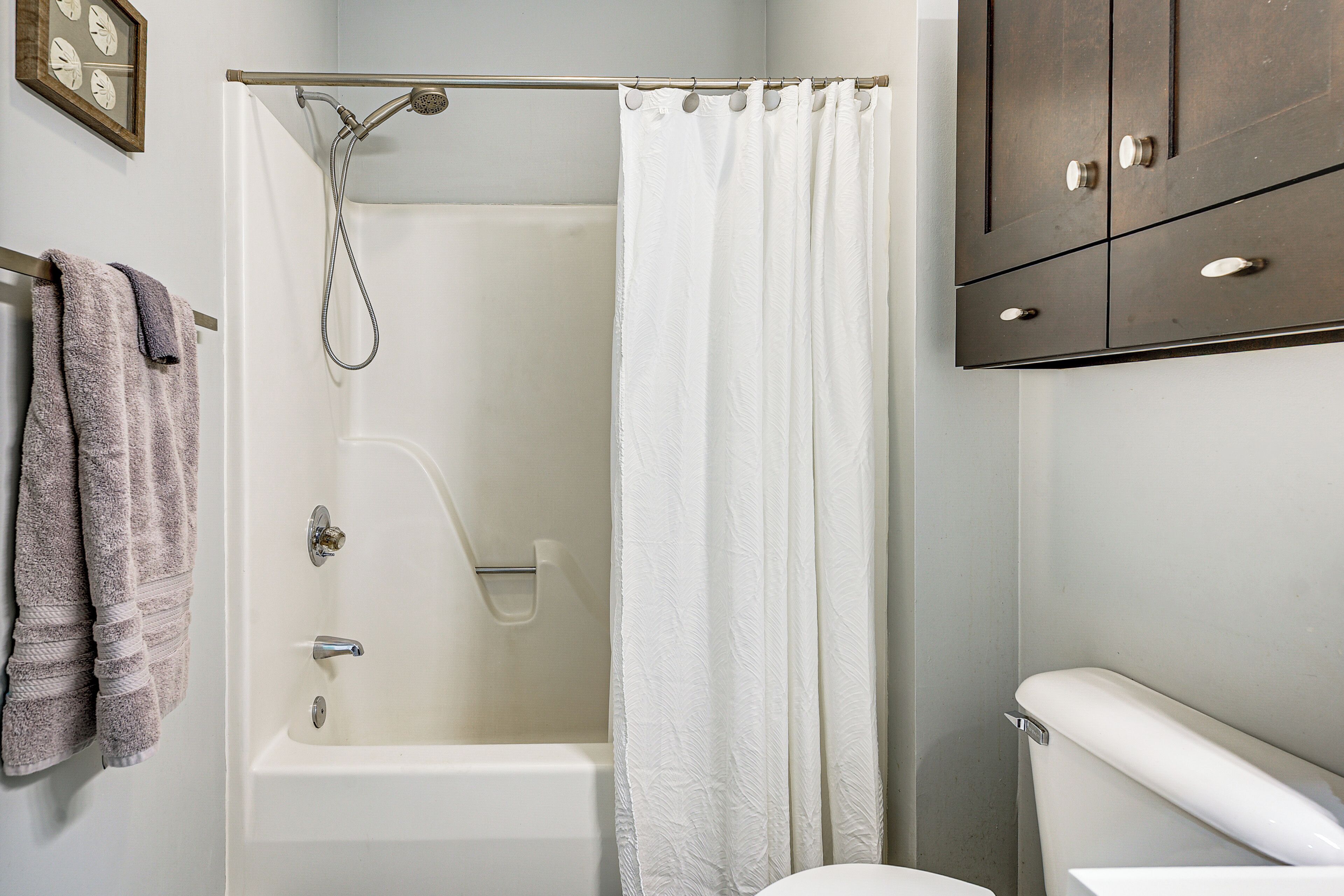 A bathroom with a bathtub, a shower curtain, a toilet, and a towel rack with towels.