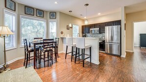 A modern kitchen with hardwood floors, a dining area with a table and chairs, and a refrigerator. - Fairway Views! Resort-style Condo in Sunset Beach (Sunset Beach)