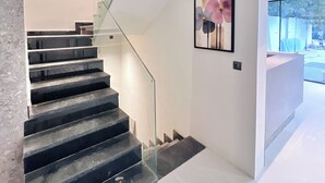 A modern staircase with glass railings and a minimalist design. - ACE STAYZ Sector57 Gurugram (Gurugram)