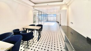 A modern dining area with a black and white tiled floor, a ceiling fan, and a view through a glass door to an outdoor space. - ACE STAYZ Sector57 Gurugram (Gurugram)