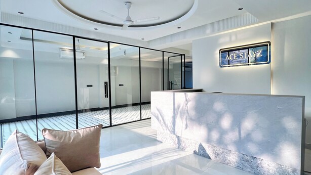 A modern interior with a central seating area, a reception desk, and a glass partition. - ACE STAYZ Sector57 Gurugram (Gurugram)