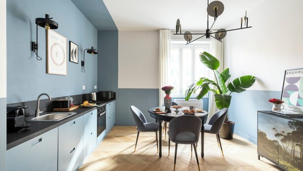 Ett modernt kök med matplats, med en svart bänkskiva, en diskho och ett matbord med stolar.