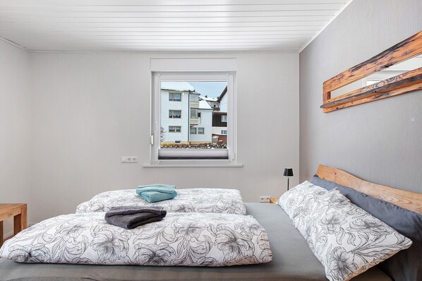 A bedroom with a bed, a window, and a view of buildings outside.