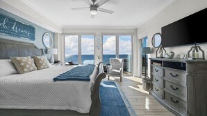 A bedroom with a large bed, a chair, a dresser, and a television. - High-end 4BR Condo w/ Gulf & Lagoon views, heated pool & hot tub (Gulf Shores)