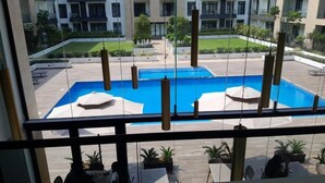 A pool area with two pools, lounge chairs, and potted plants. - Cozy Nuggets at Embassy Gardens (Accra)
