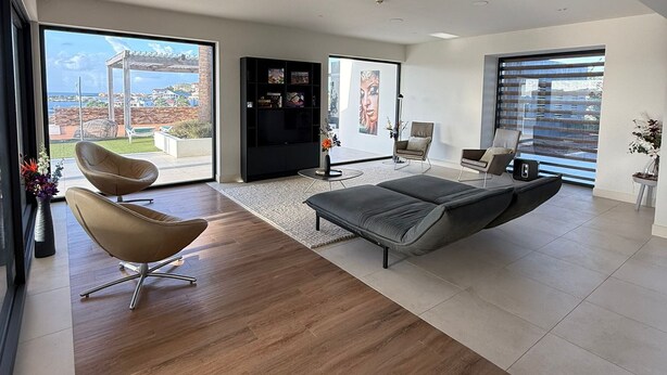 A modern living room with a large window, a sofa, a chair, and a TV. - VILLA MAY, PRIVACY, FANTASTIC VIEWS AND 10 MIN FROM JAN THIEL (Willemstad)