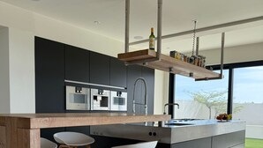 A modern kitchen with a central island, bar stools, and built-in appliances. - VILLA MAY, PRIVACY, FANTASTIC VIEWS AND 10 MIN FROM JAN THIEL (Willemstad)
