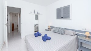 Un dormitorio con cama, mesitas de noche, armario y una ventana con contraventanas.