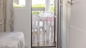 Una habitación con cama, ventana y vistas a un patio exterior con mesa y sillas.
