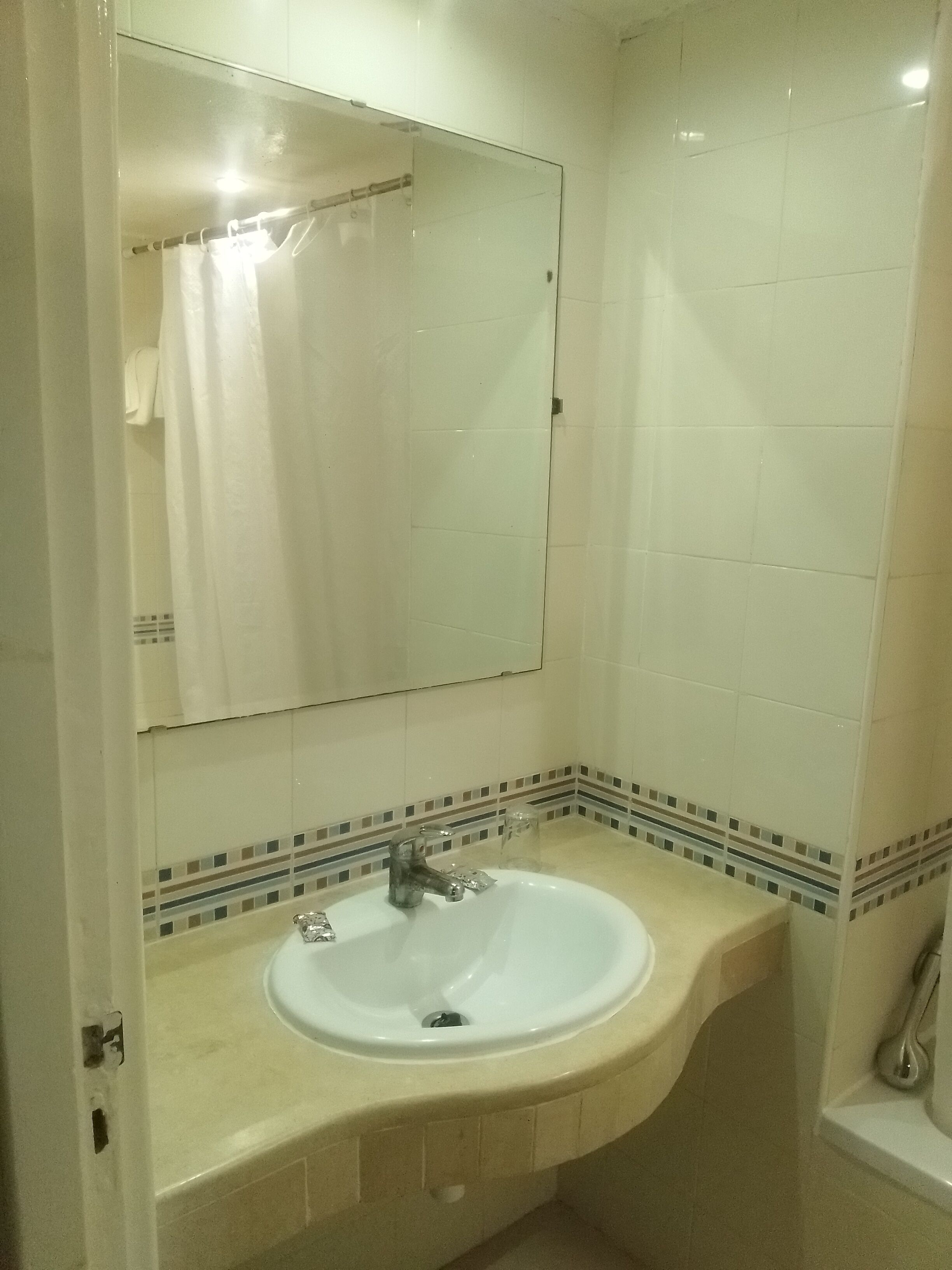 A bathroom with a white sink, a mirror, and a shower curtain.