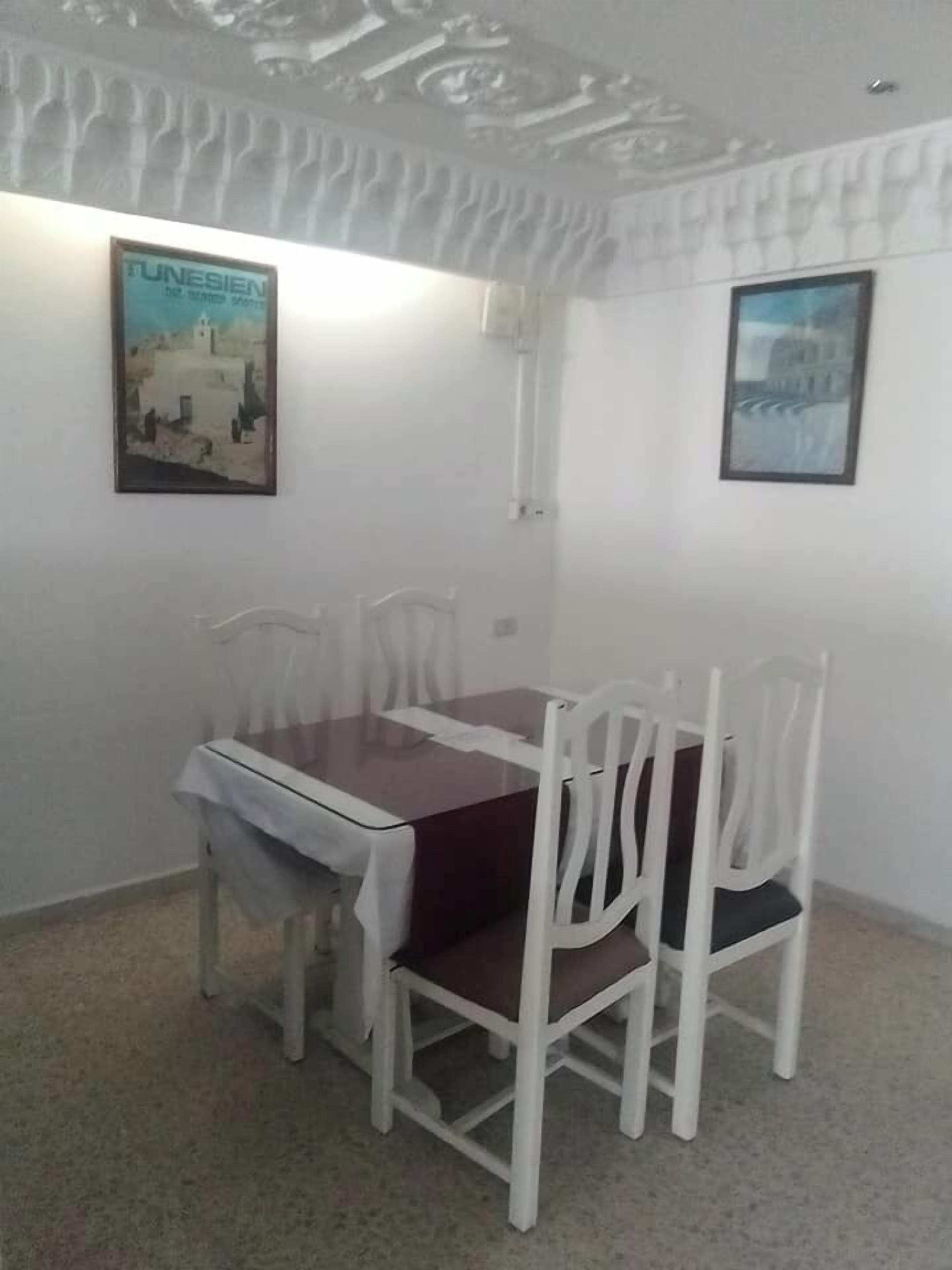 A dining area with a table and chairs, a framed picture on the wall, and a ceiling with a textured design.