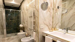 Un baño moderno con tocador de mármol, un bidé, ducha con mampara de vidrio y un espejo grande.