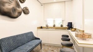 Una cocina compacta con una barra y taburetes, un lavabo y una cafetera.