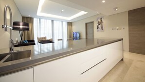 A modern kitchen with a large island, built-in appliances, and a sleek design. - Luxury 1BR at Sterling East Burj Views (Dubai)