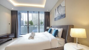 A modern hotel room with a large bed, a bedside table with a lamp, a view of the city through large windows, and a painting on the wall. - Luxury 1BR at Sterling East Burj Views (Dubai)