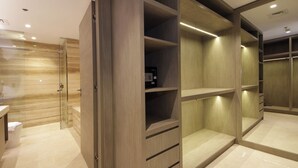 A modern bathroom with a glass shower enclosure, a wooden vanity, and a walk-in closet with built-in shelves and drawers. - Luxury 1BR at Sterling East Burj Views (Dubai)