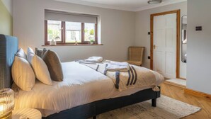 Una camera da letto con un letto, un comodino, una finestra, una sedia e una porta.