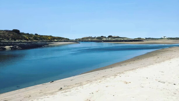 A coastal landscape with a sandy beach and calm water. - Swan Cottage (Gaerwen)