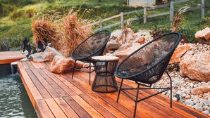 A wooden deck with two black wire mesh chairs and a small round table. - Exclusive A-Frame chalet with private pool. (Itajubá)