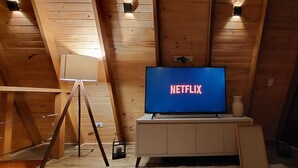 A room with wooden walls and a television displaying the Netflix logo. - Exclusive A-Frame chalet with private pool. (Itajubá)