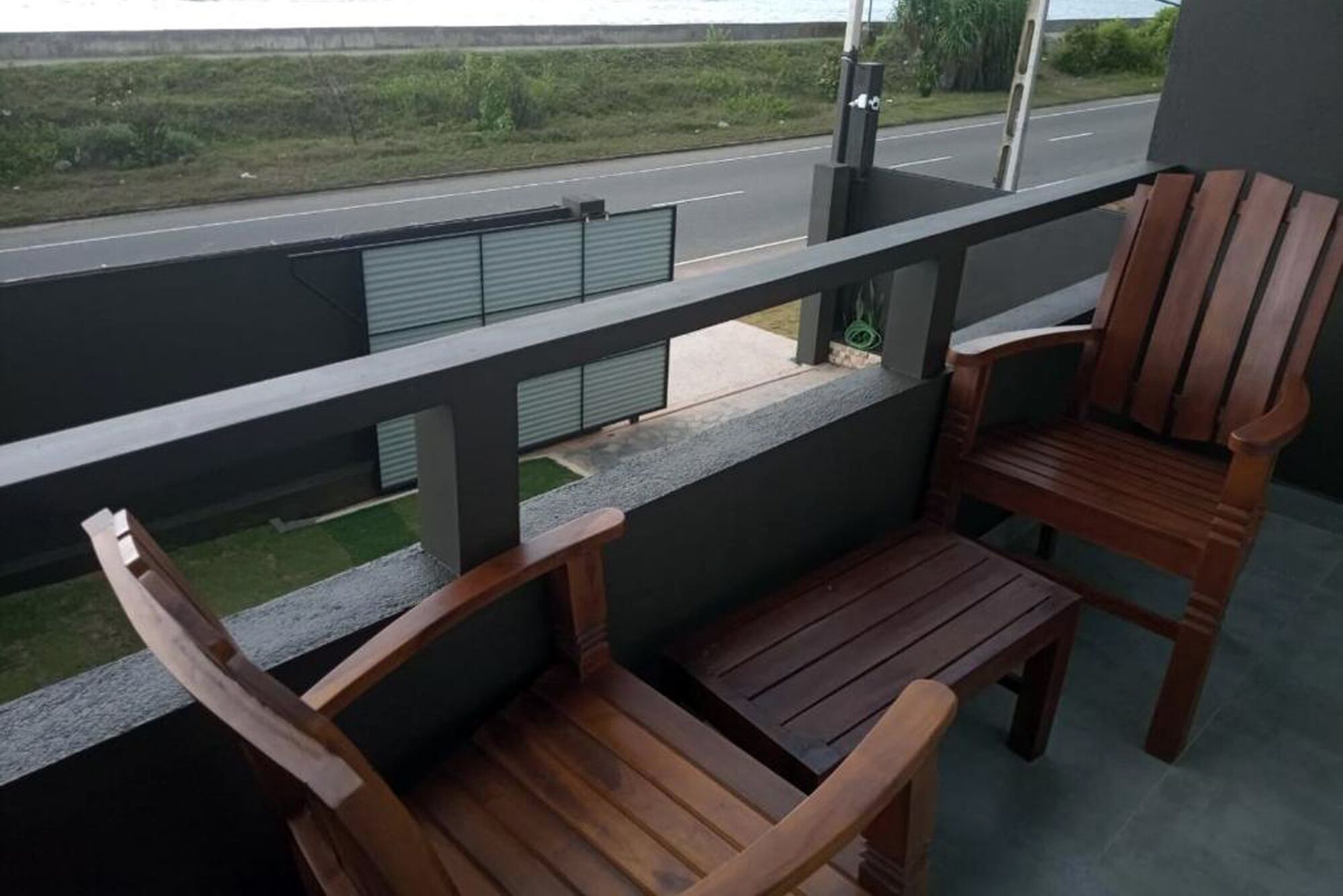 A balcony with two wooden chairs and a small table.