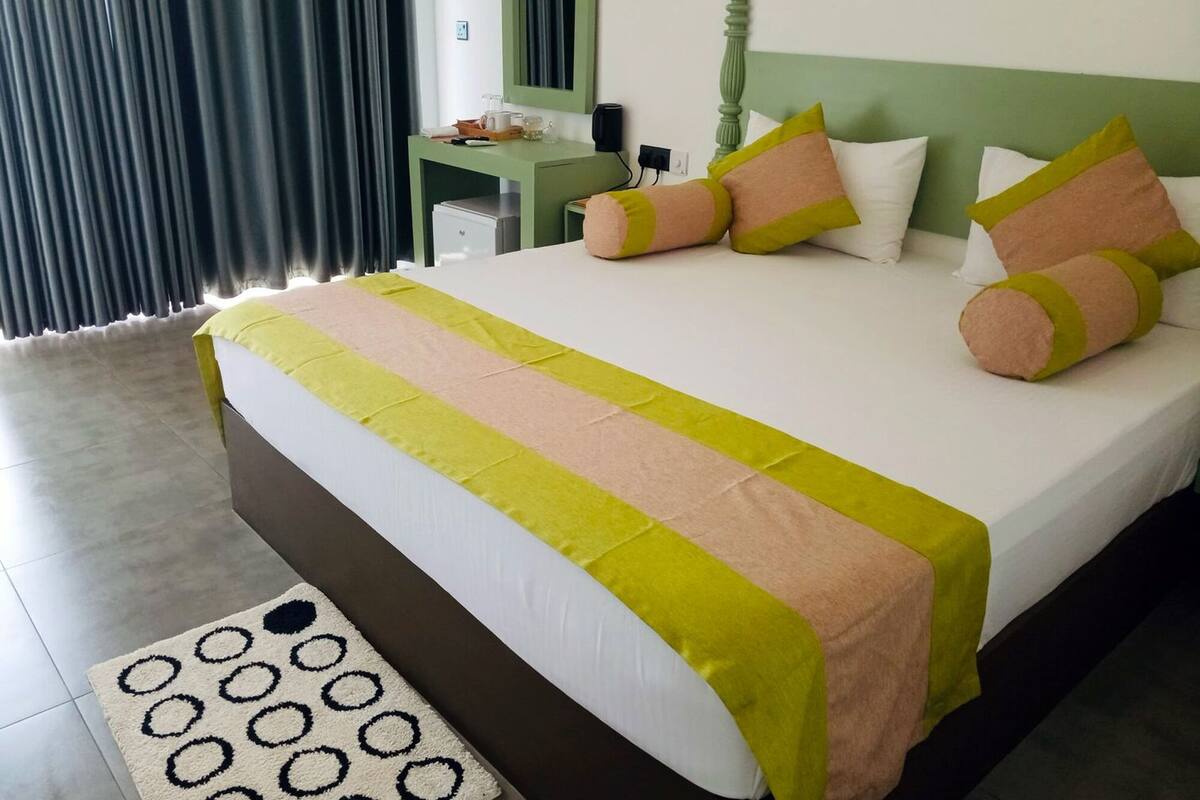 A neatly made bed with a striped bedspread, a bedside table with a lamp, and a mirror on the wall.
