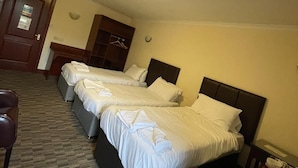 Una habitación de hotel con dos camas, un escritorio, una silla y una mesita.