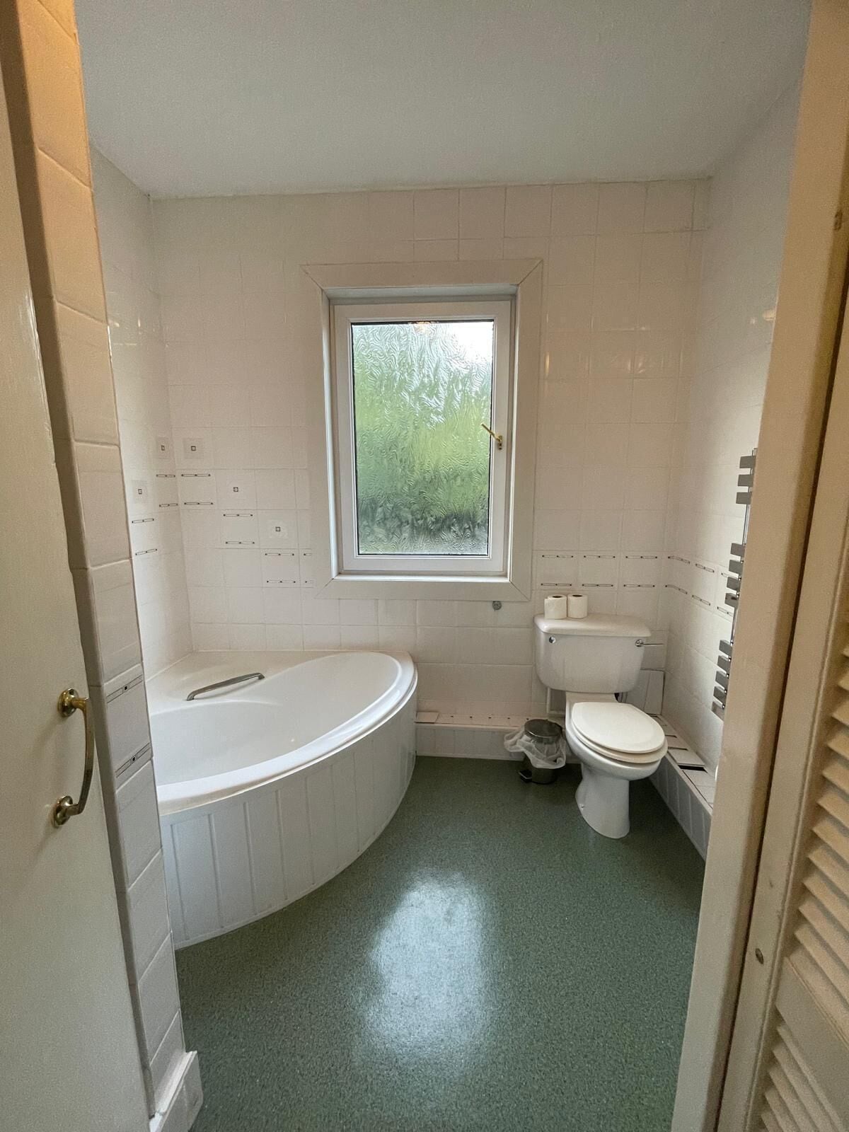 Ein Badezimmer mit Badewanne, Toilette und einem Fenster.