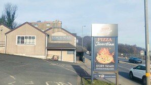 Un edificio con la leyenda 'LOCHWAY HOTEL' y un cartel que anuncia 'PIZZA Junction', un restaurante de pizza.